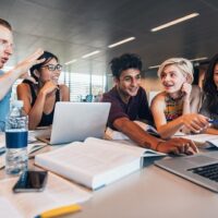 University,Students,Using,Laptop,In,A,Library.,Students,Working,Together